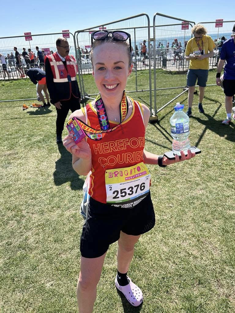 Kimberley at the end of the marathon smiling and holding up her medal